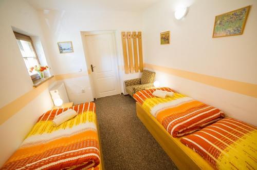 a room with two beds and a chair in it at Pension Jana in Český Krumlov