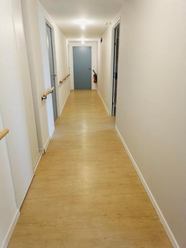 un long couloir avec des murs blancs et du parquet. dans l'établissement Quiet shared getaway, à Giberville