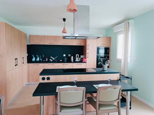 une cuisine avec un comptoir noir et des placards en bois dans l'établissement Quiet shared getaway, à Giberville