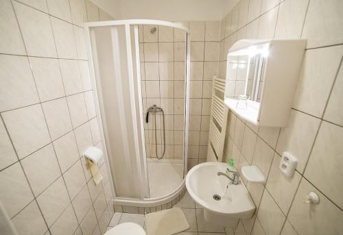 a white bathroom with a shower and a sink at Pension Jana in Český Krumlov