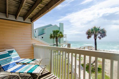a beach house balcony with a chair and the ocean at Waves N At by Bryant Real Estate in Kure Beach