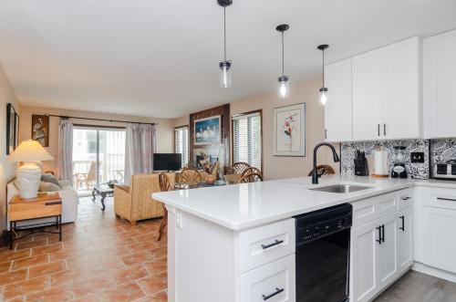 a kitchen with white cabinets and a living room at Waves N At by Bryant Real Estate in Kure Beach