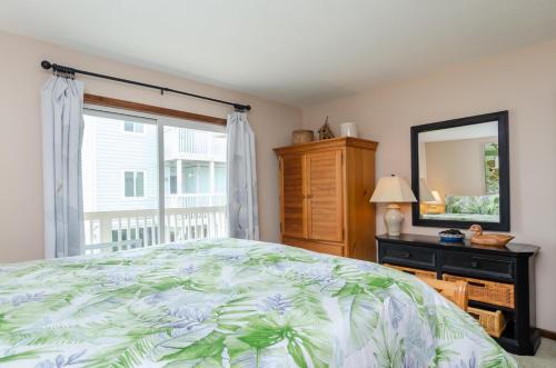 a bedroom with a bed and a mirror and a window at Waves N At by Bryant Real Estate in Kure Beach