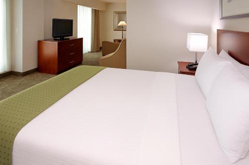 a large white bed in a hotel room with a television at LIC Manhattan View Hotel in Queens