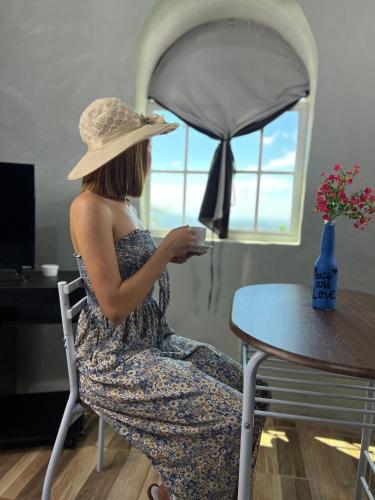 une femme assise à une table avec une tasse de café dans l'établissement Las Terrazas de el Alto, à Chalatenango