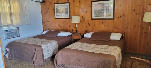 two beds in a hotel room with wooden walls at Amaris Inn in Redfield