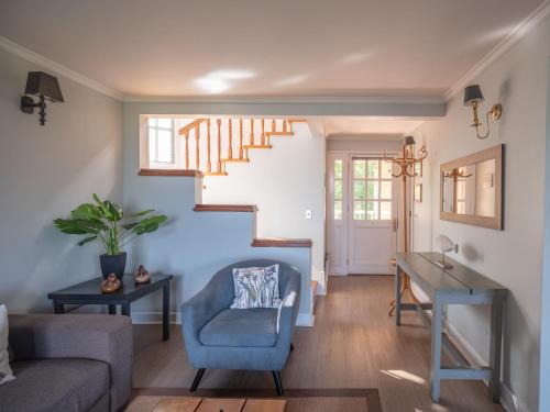 a living room with a blue chair and a staircase at Bahía Coique in Futrono