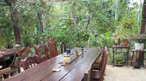 a wooden table in a garden with bottles and chairs at Kakao Lodge & Garden Río Celeste in Bijagua