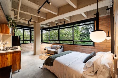 a bedroom with a large bed and large windows at Otalu Suites in Medellín