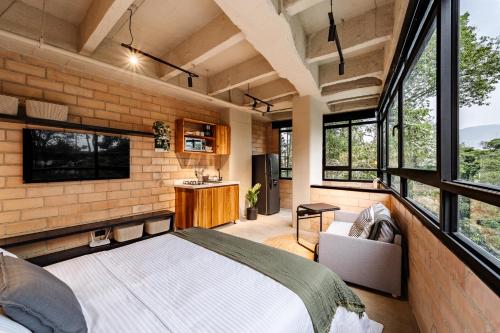 a bedroom with a large bed in a room with windows at Otalu Suites in Medellín