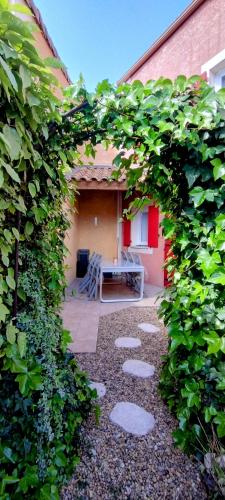 une vue d'un patio à travers une haie dans l'établissement Maison cosy au bord du canal, piscine et parking, à Béziers