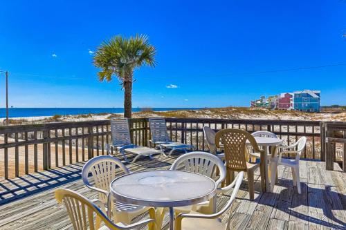 a deck with tables and chairs and the beach at Fort Morgan Townhomes E7 in Fort Morgan