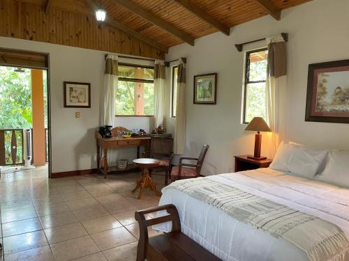 a bedroom with a bed and a desk and windows at Kakao Lodge & Garden Río Celeste in Bijagua