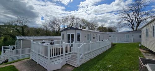 a large white house with a deck on a yard at Stunning 2 bed Luxury Caravan at Hoburne Devon Bay, with Hot Tub and sea view in Paignton