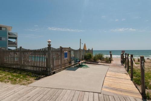 a wooden walkway to the beach with a fence at Rudicile by Bryant Real Estate in Kure Beach