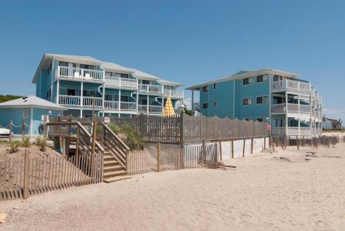a row of buildings on the beach next to the sand at Rudicile by Bryant Real Estate in Kure Beach