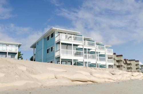 a blue building sitting on top of a sandy beach at Rudicile by Bryant Real Estate in Kure Beach
