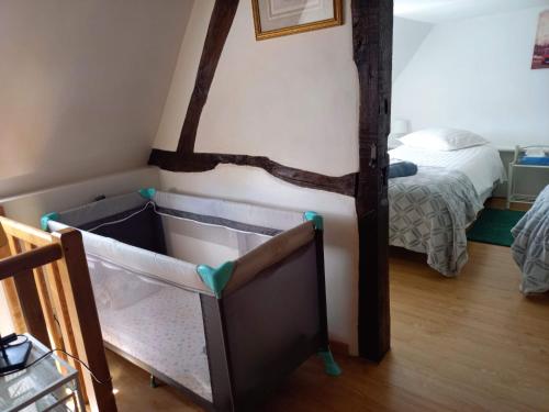 a baby crib in a room with a bed at Cosy Little Cottage in Landepéreuse