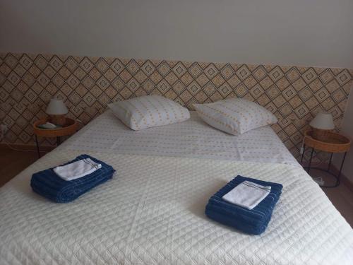 a bed with two blue bags on top of it at Cosy Little Cottage in Landepéreuse