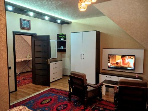 a living room with a tv and a desk and a chair at Dom Semya Deluxe Gusar in Qusar