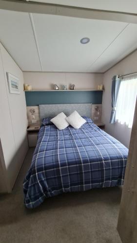 a bedroom with a blue and white bed with two pillows at Stunning 2 bed Luxury Caravan at Hoburne Devon Bay, with Hot Tub and sea view in Paignton
