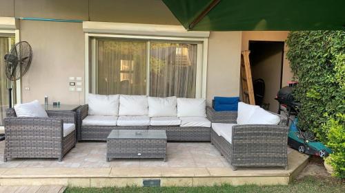 a patio with a white couch and wicker chairs at Standalone villa in ‘Izbat Yūsif Barrādah