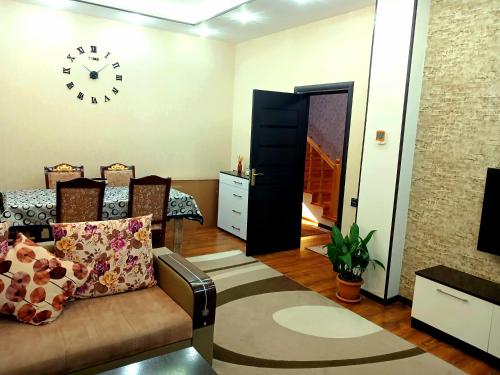 a living room with a couch and a clock on the wall at Dom Semya Deluxe Gusar in Qusar