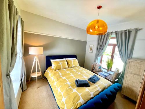a bedroom with a bed with a yellow and white comforter at Wicket Green Cottage Hayfield in Hayfield