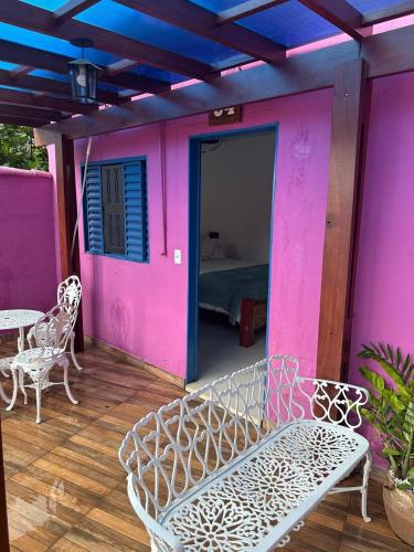 a porch with a white bench and a pink wall at Pousada Refúgio Encantado in Goiás
