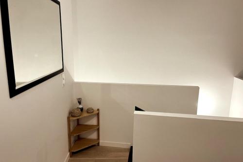 Cette chambre blanche dispose d'une étagère et d'un miroir. dans l'établissement Modern bright flat with outside terrace, à Biarritz