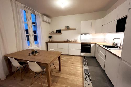 une cuisine avec une table en bois et des armoires blanches dans l'établissement Modern bright flat with outside terrace, à Biarritz