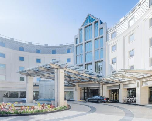 a large white building with a car parked in front at Regent Santa Monica Beach in Los Angeles