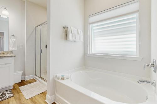 a white bathroom with a tub and a window at Windmark - The Soaring Gull in Highland View