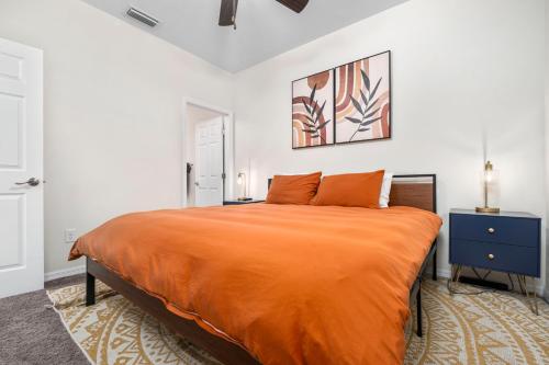 a bedroom with a large bed with an orange blanket at Beautiful Home, Walk to UF, Newly built in Gainesville