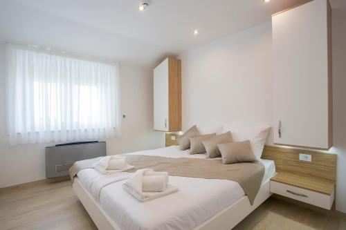 een witte slaapkamer met een groot bed met witte kussens bij Adrion Aparthotel in Pula