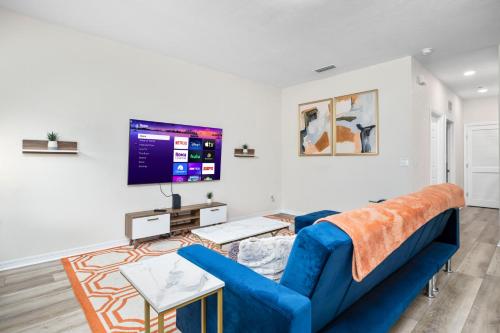 a living room with a blue couch and a tv at Beautiful Home, Walk to UF, Newly built in Gainesville