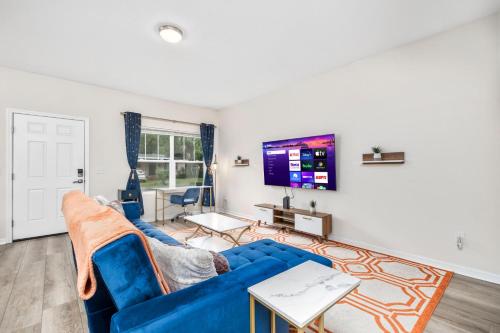a living room with a blue couch and a flat screen tv at Beautiful Home, Walk to UF, Newly built in Gainesville