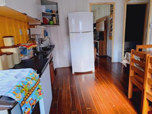 a kitchen with a white refrigerator and a wooden floor at Casa da vó in Morretes
