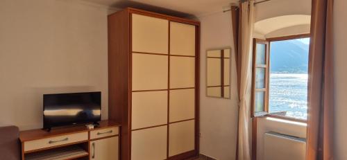 a room with a large cabinet with a television and a window at Gospar Apartments in Kotor