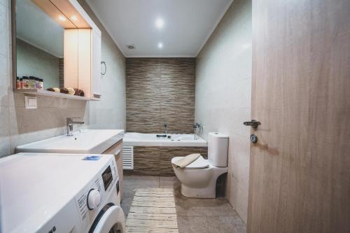 a bathroom with a toilet and a sink and a washing machine at Stylish home - comfortable holidays near the beach. in Panormos Rethymno