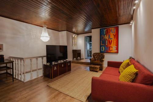 a living room with a red couch and a flat screen tv at BABhouse Casa D'ouro in Nagoselo do Douro
