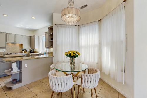 a kitchen with a glass table with chairs and a vase of flowers at Rancho Mirage Vacation Villa in Rancho Mirage