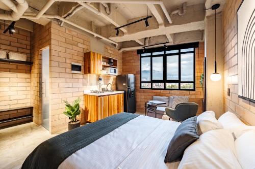a bedroom with a large bed and a kitchen at Otalu Suites in Medellín