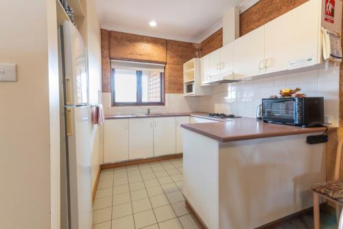 a kitchen with white cabinets and a microwave at Mud Hut Motel in Coober Pedy