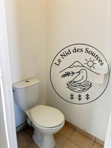 a bathroom with a toilet with a sign on the wall at Le Nid des Sources in Montbrun-les-Bains
