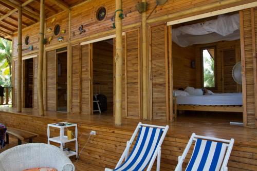 a bedroom with two chairs and a bed on a deck at Casa Palmeras Isla Portete in Isla Zapotal