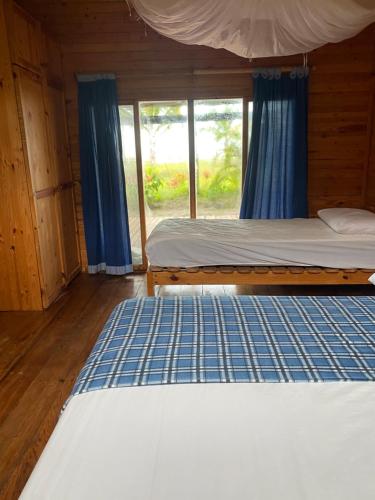 a bed in a wooden room with a window at Casa Palmeras Isla Portete in Isla Zapotal
