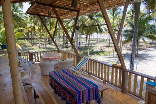 a porch with chairs and a table and palm trees at Casa Palmeras Isla Portete in Isla Zapotal