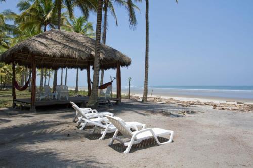 a beach with chairs and a gazebo and the ocean at Casa Palmeras Isla Portete in Isla Zapotal