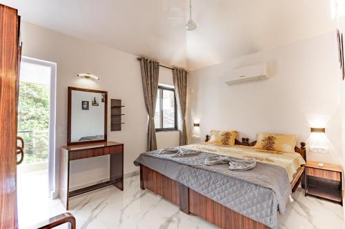 a bedroom with a large bed and a mirror at Modern 1BHK Condo With Pool 3min Walk To Beach in Orlim